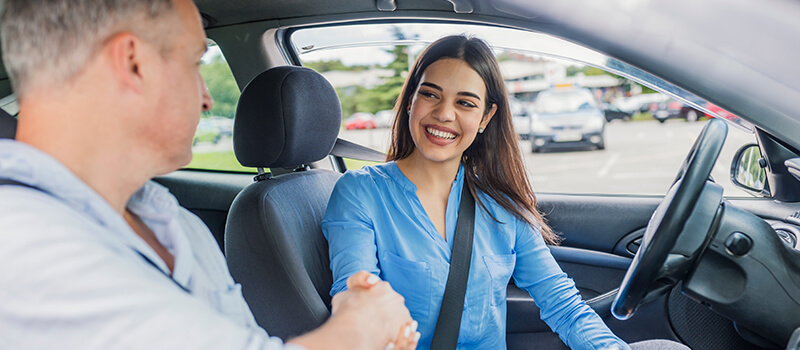 man and woman shaking hands in car