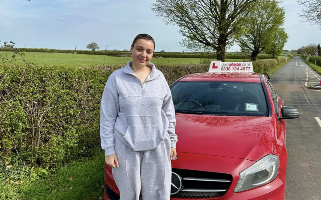 Danika Hill standing by red car