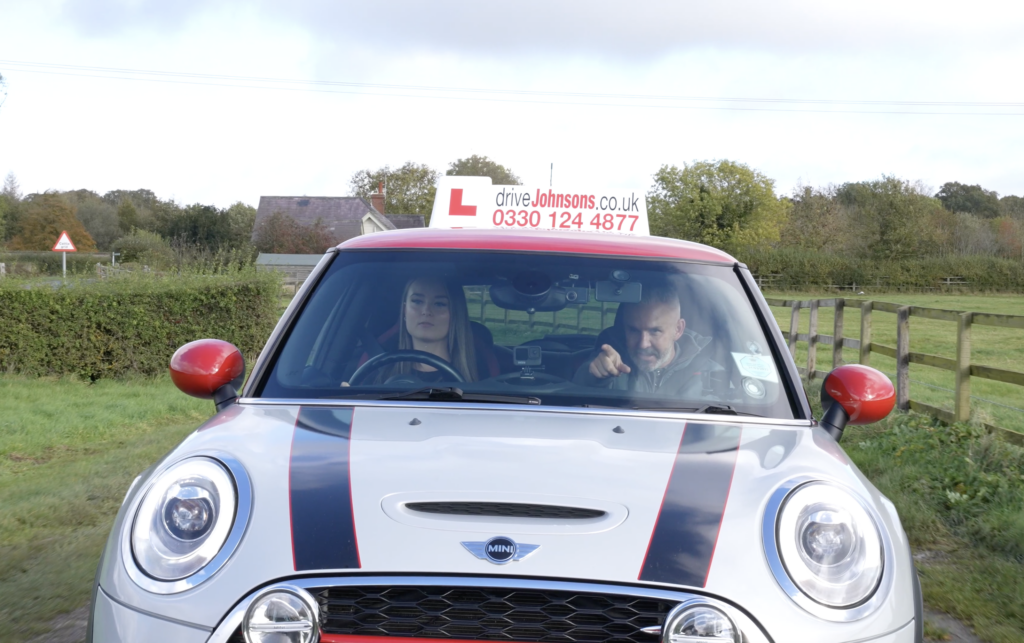 Driving instructor pointing out hazard to learner driver in car