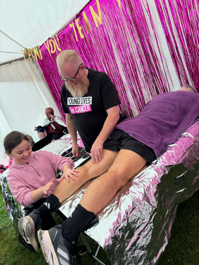 Freya giving Anthony a leg massage with the Young Lives Vs Cancer team