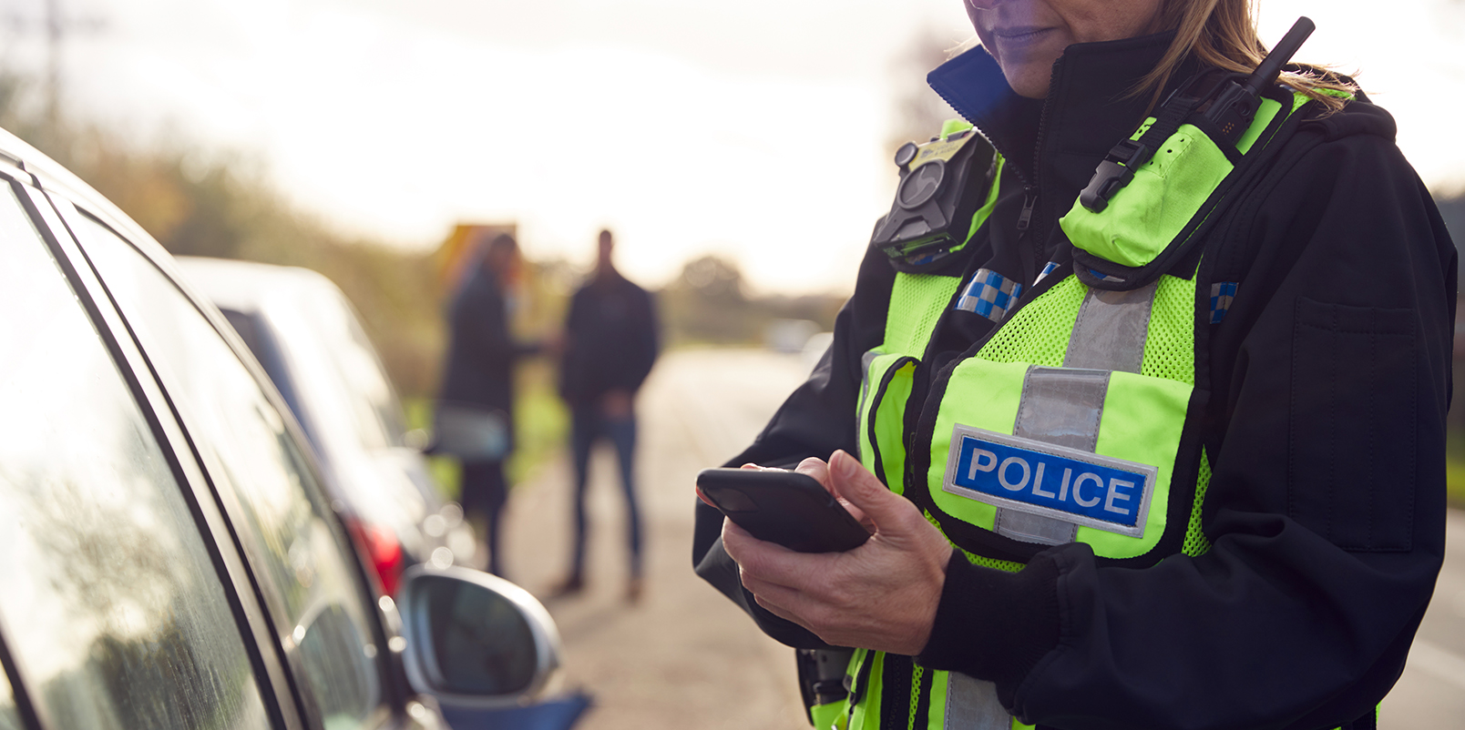 Police woman taking notes by a car