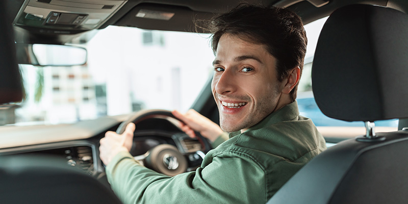 A driver in a car looking back over shoulder at camera