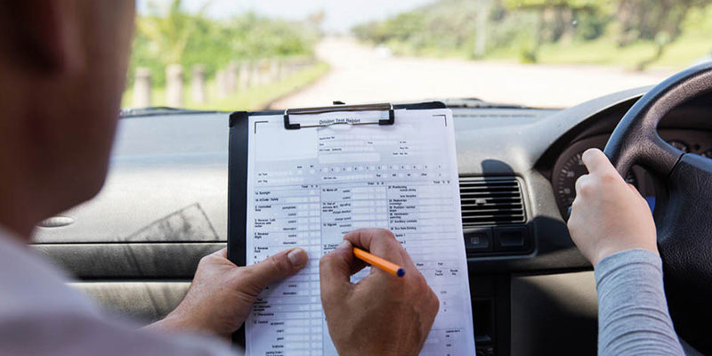 An examiner marking a learner in the car on their test