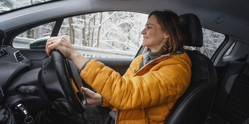 A happy woman driving in snowy conditions