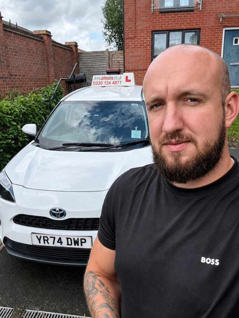 Dawid Prudzilko standing next to his car with roof sign