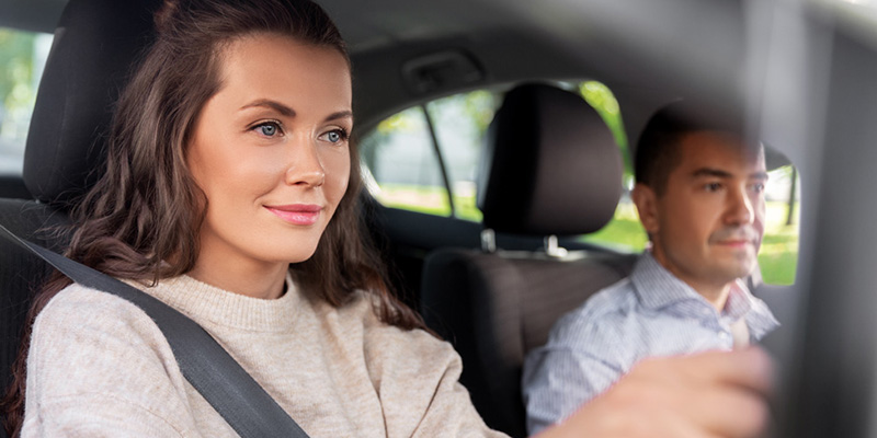 Smiling learner behind the wheel with instructor nexto to her