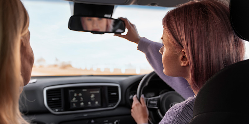 Female driver adjusting car mirror