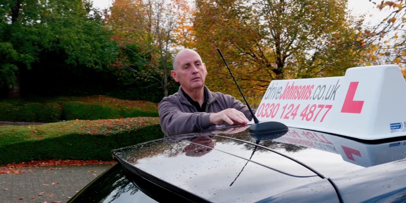 driveJohnson's instructor adjusting their roof sign on car