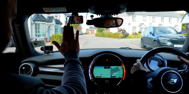 Instructor holding their hand up gesturing the learner to stop the car