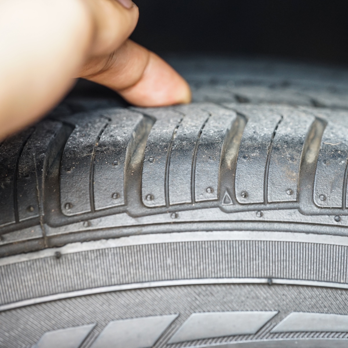 Person checking the tyre tread depth with their finger