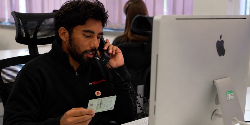 Man looking down at a provisional driving licence whilst on the phone
