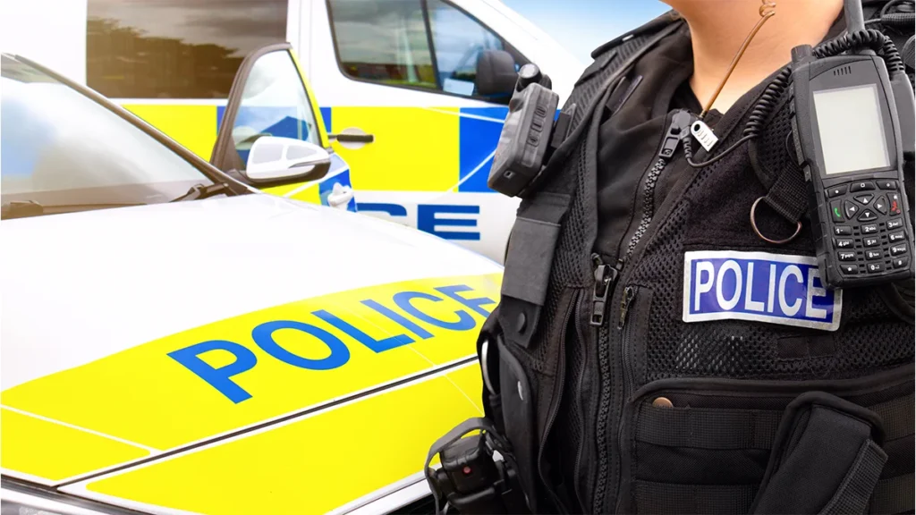 Police officer with radio beside a police car