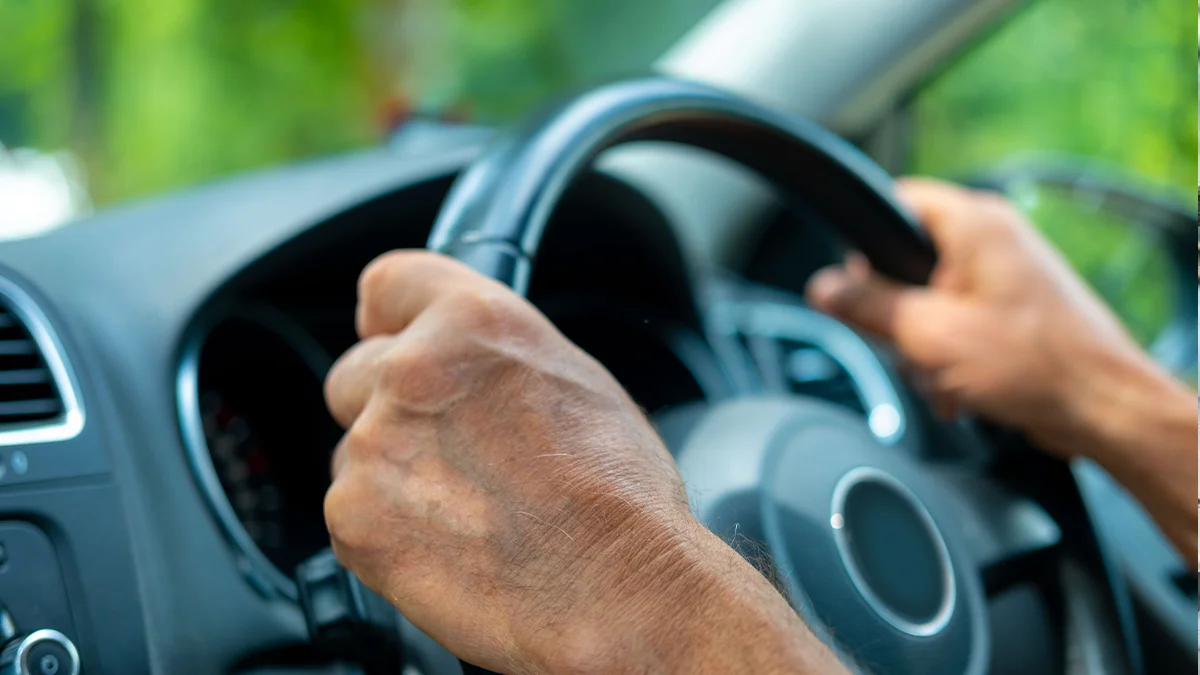 Both hands gripping a steering wheel